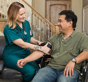 Healthcare provider taking man's blood pressure at home.